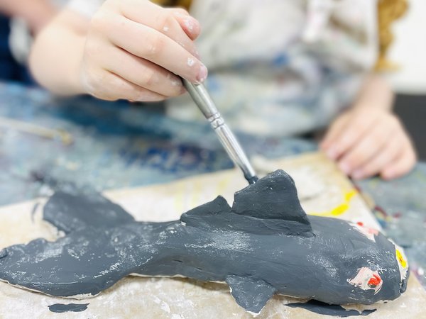 Child painting shark in Cool Sharks, clay sculpting workshop