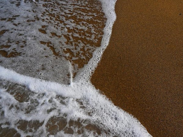 a wave washing across sand