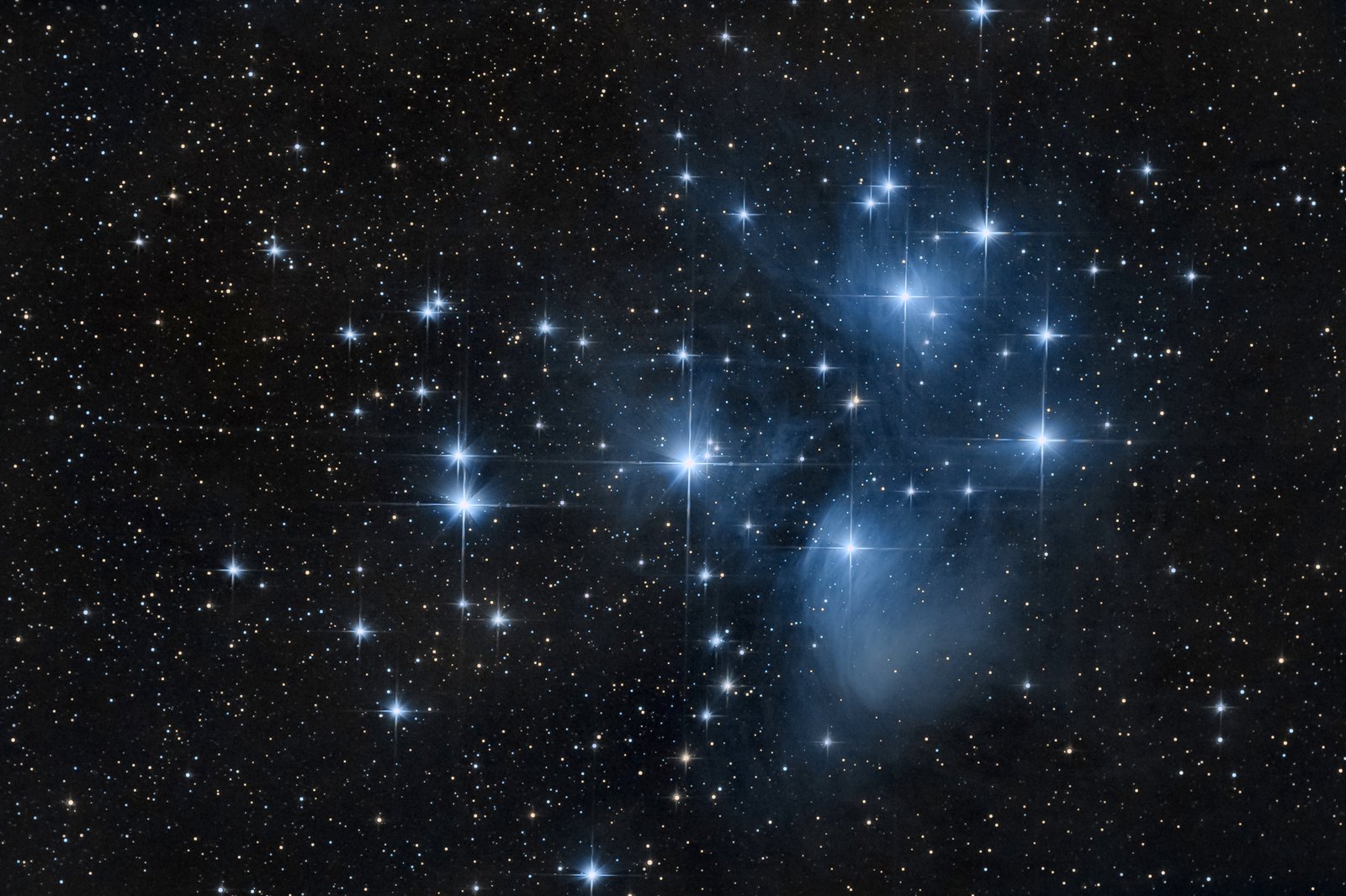 The Pleiades star cluster, also known as the Seven Sisters, showing bright blue stars surrounded by nebulous gas and dust.